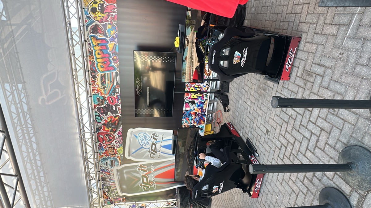 Two racing simulator rigs set up at an outdoor brand activation event
