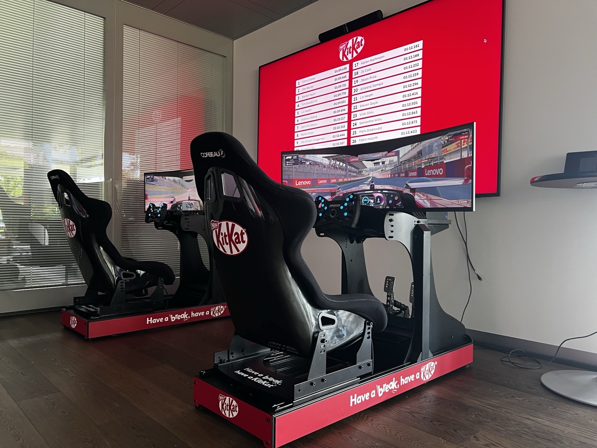 Racing simulator rigs with a client-branded lap time leaderboard on a large screen